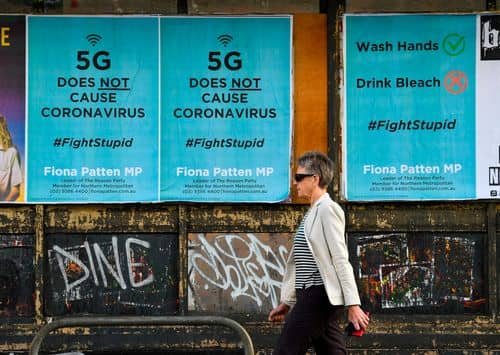 En fodgænger passerer plakater, der afviser konspirationen om, at 5G-teknologi forårsager coronavirus, midt i COVID-19 pandemien i en forstad til Melbourne den 24. juni 2020.