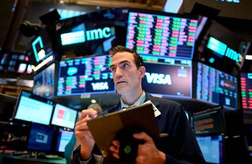 Mægler på børsen i New York med computerskærme i baggrunden