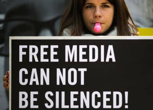 Demonstrant holder skilt med teksten "Free media can not be silenced".