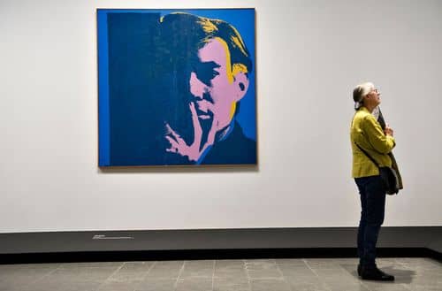 Kvinde på kunstudstilling på Loiusiana med selvportræt af Andy Warol i baggrunde