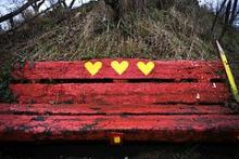 Rød bænk lavet af jernbaneesveller på Christiania med fristadens symbol, tre gule hjerter.