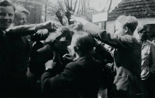 En gruppe mennesker står rundt om en tyskerpige, som klippes efter befrielsen. Ukendt sted.