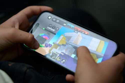 Nærbillede af hænder, der holder en smartphone med spillet Roblox åbent på skærmen. Billedet illustrerer børn og unges brug af digitale spil og online platforme.